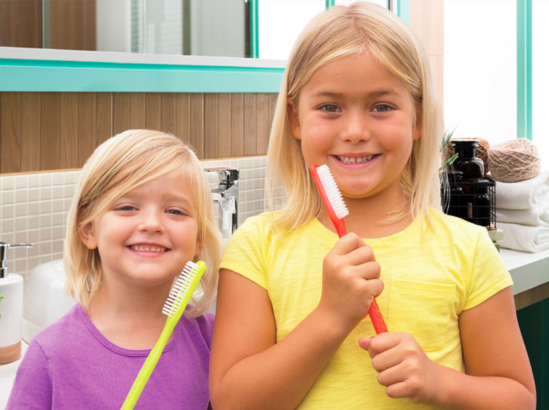 two girls holding giant toothbrushes